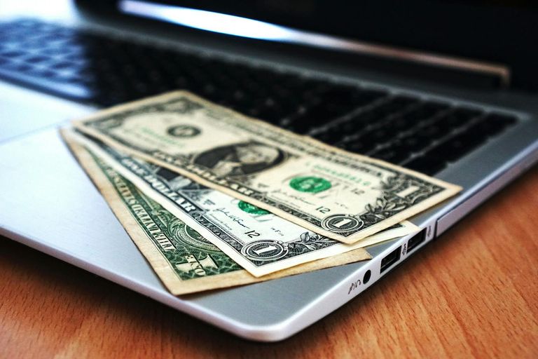 banknoty na laptopie - metafora kredytu konsolidacyjnego online