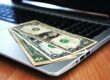 banknoty na laptopie - metafora kredytu konsolidacyjnego online